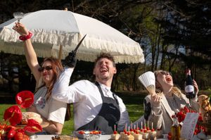 Cheerful chefs laughing and celebrating outdoors at a festive culinary event with desserts.