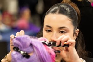 Une femme coupe avec soin des cheveux d'un violet éclatant à l'aide de ciseaux lors du concours MAF de Vendée