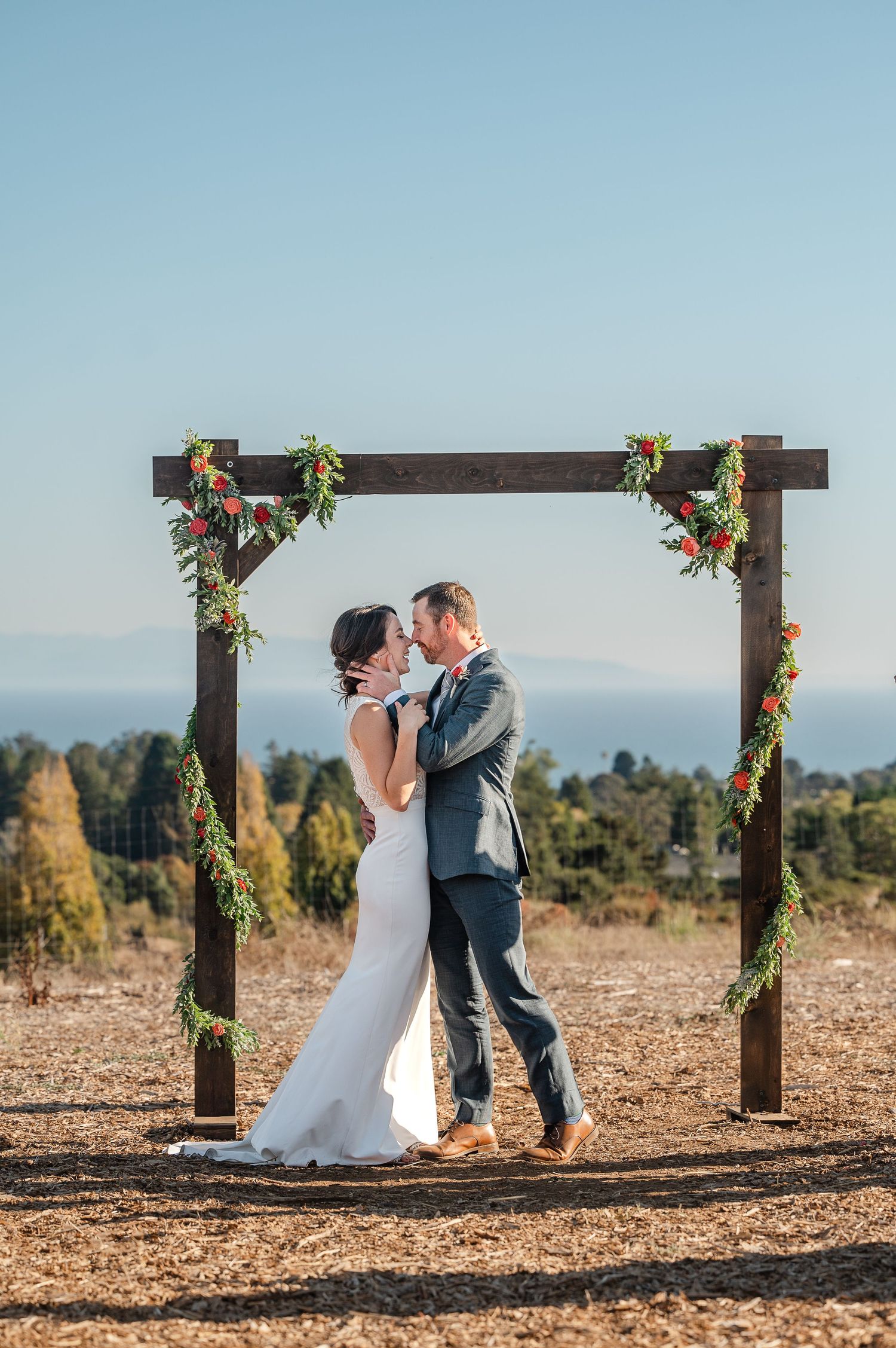 Joyful bride and groom lifted by guests at wedding reception with bubbles and string lights.