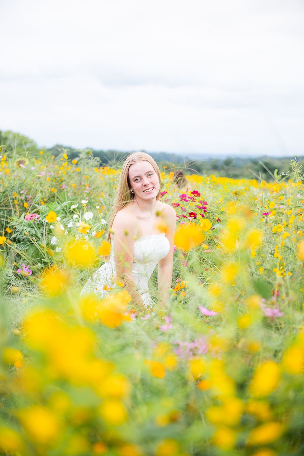 A joyful summer portrait session in a vibrant field of yellow wildflowers on a bright sunny day.
