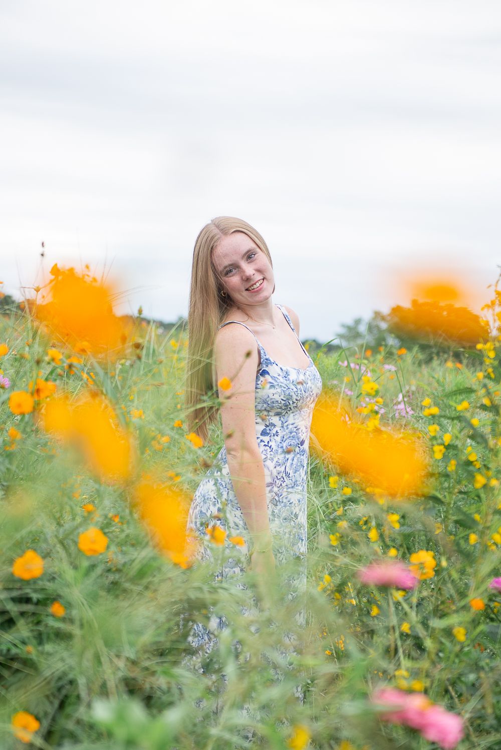 Candid portraits among bright orange and pink wildflowers in a summer meadow with soft natural lighting.