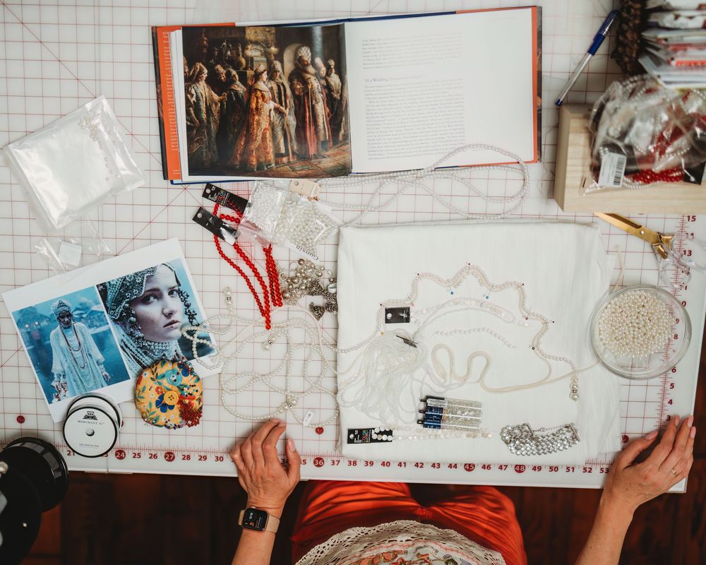 Overhead view of hands working on sketches and drawings with grid paper and rulers.