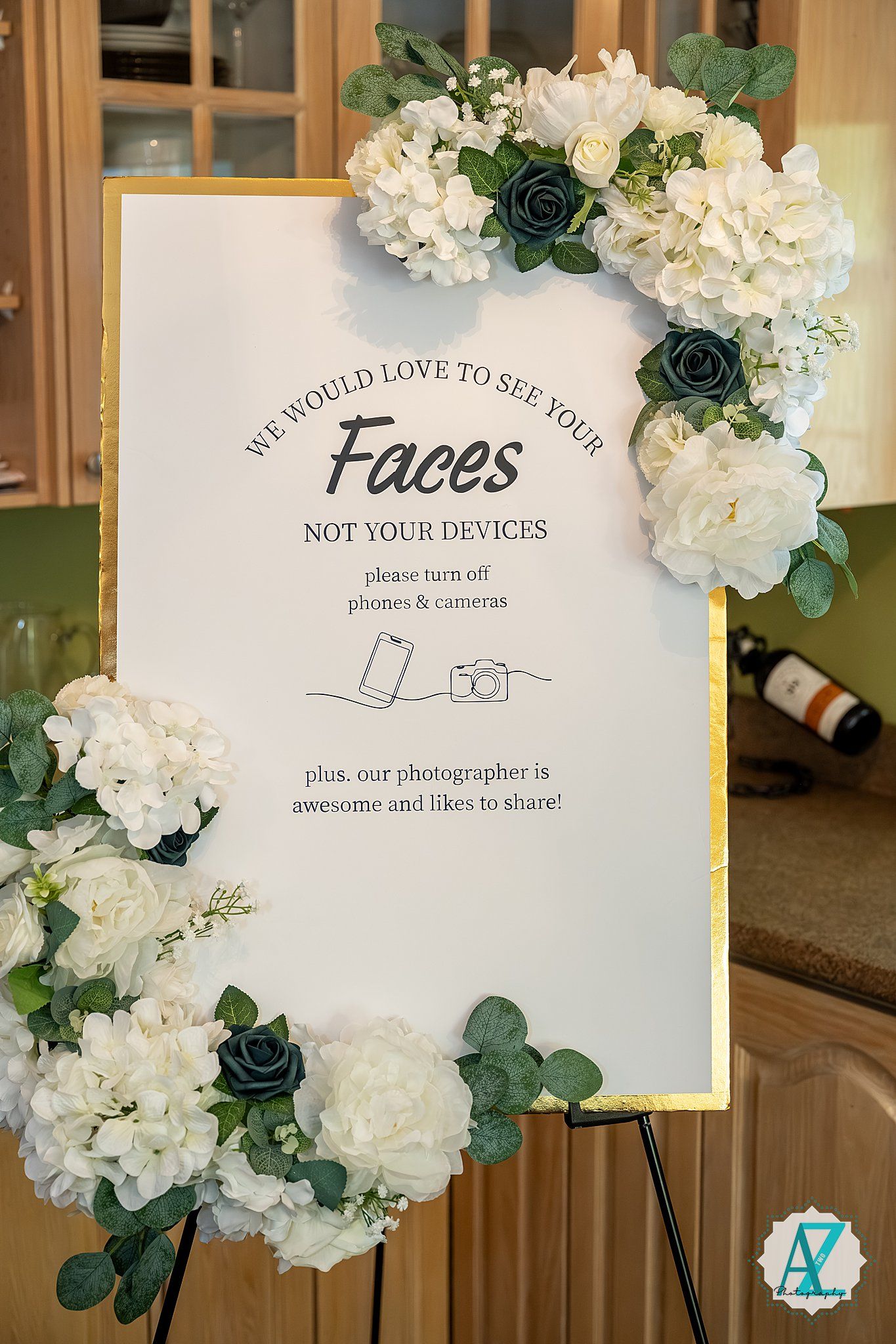 Wedding sign decorated with white hydrangeas and navy blue roses asking guests to focus on the ceremony rather than devices.