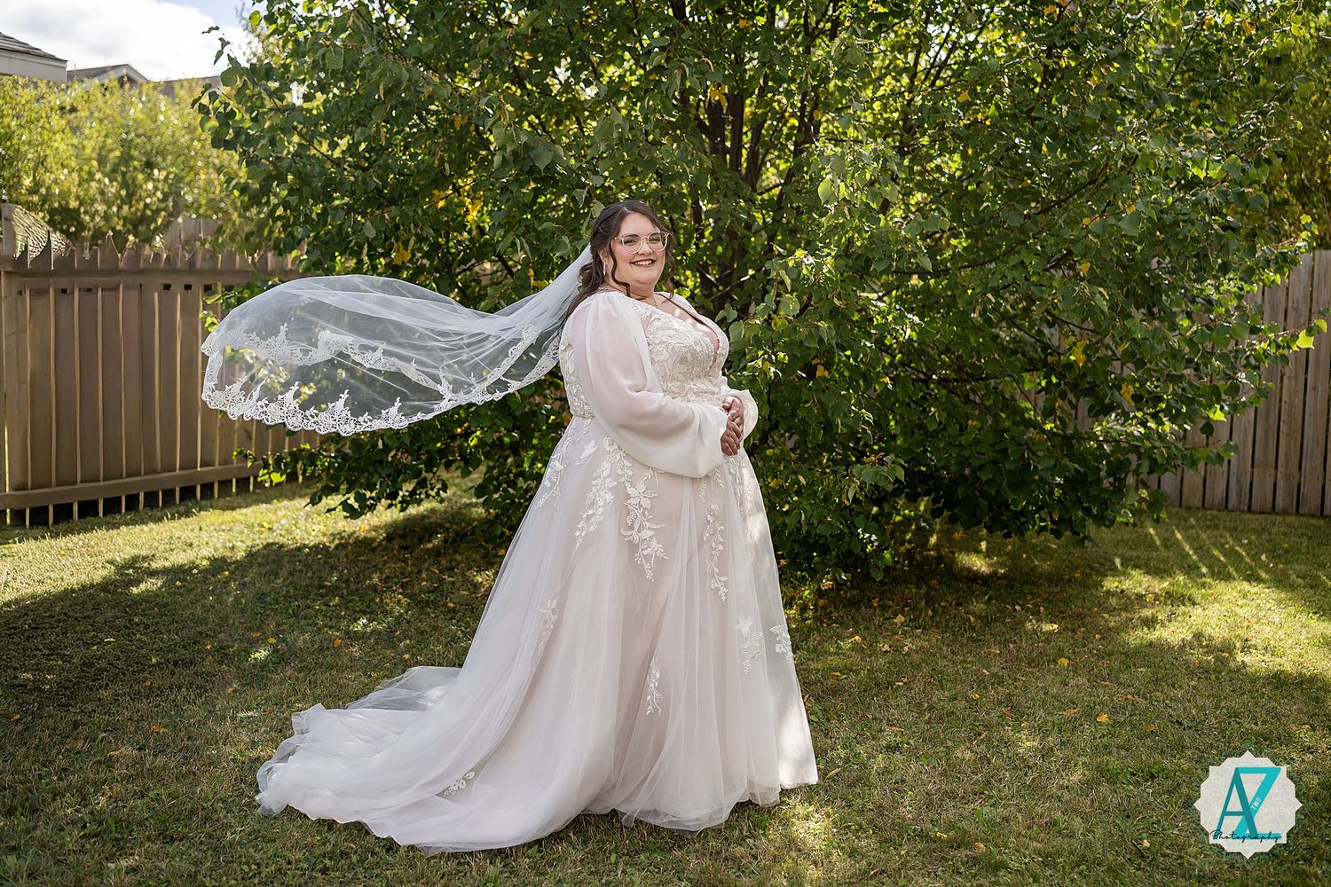 A wedding dress with delicate lace details flows gracefully in a sunlit garden setting.
