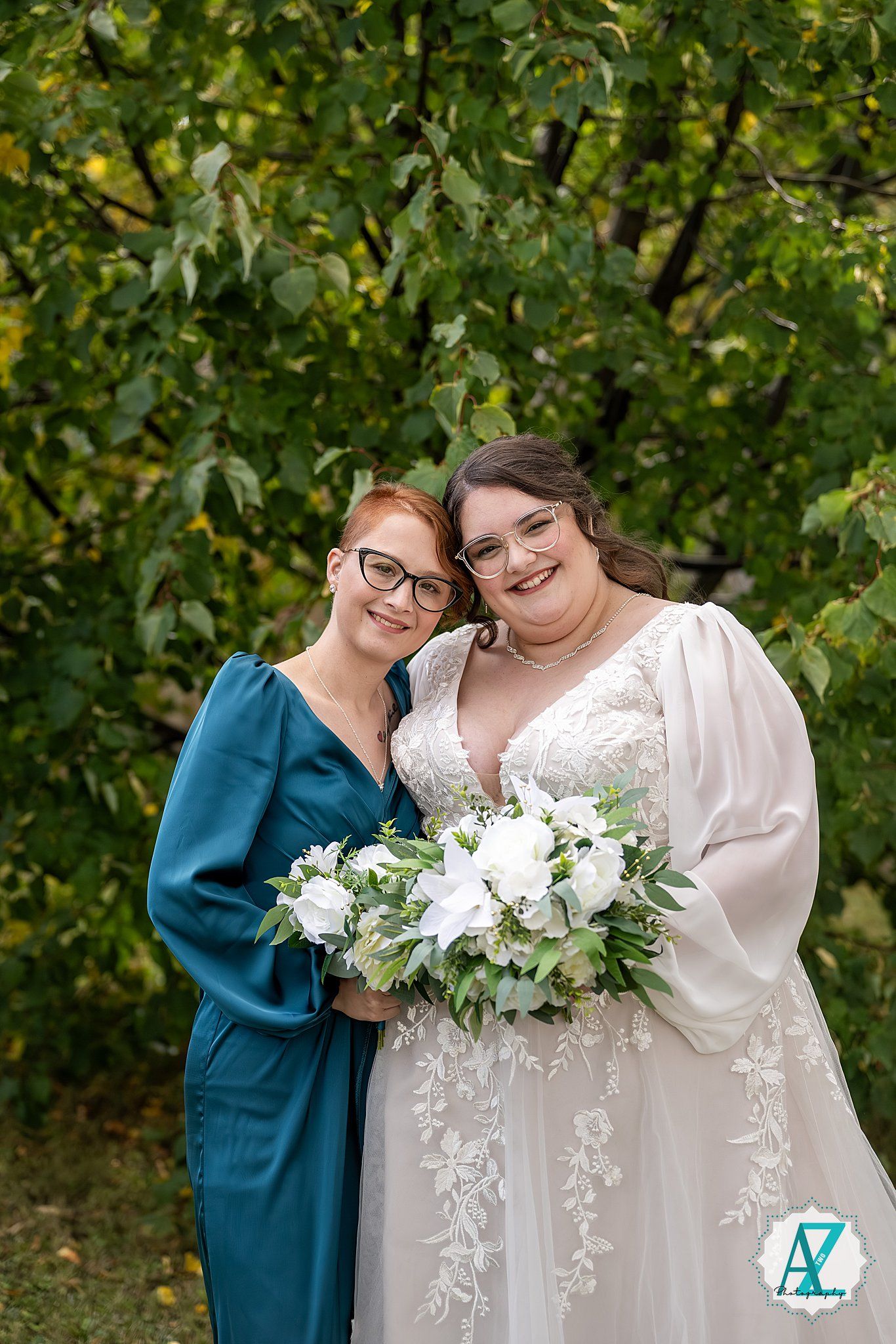 Two people share a joyful moment together outdoors with white floral bouquet against green foliage background.