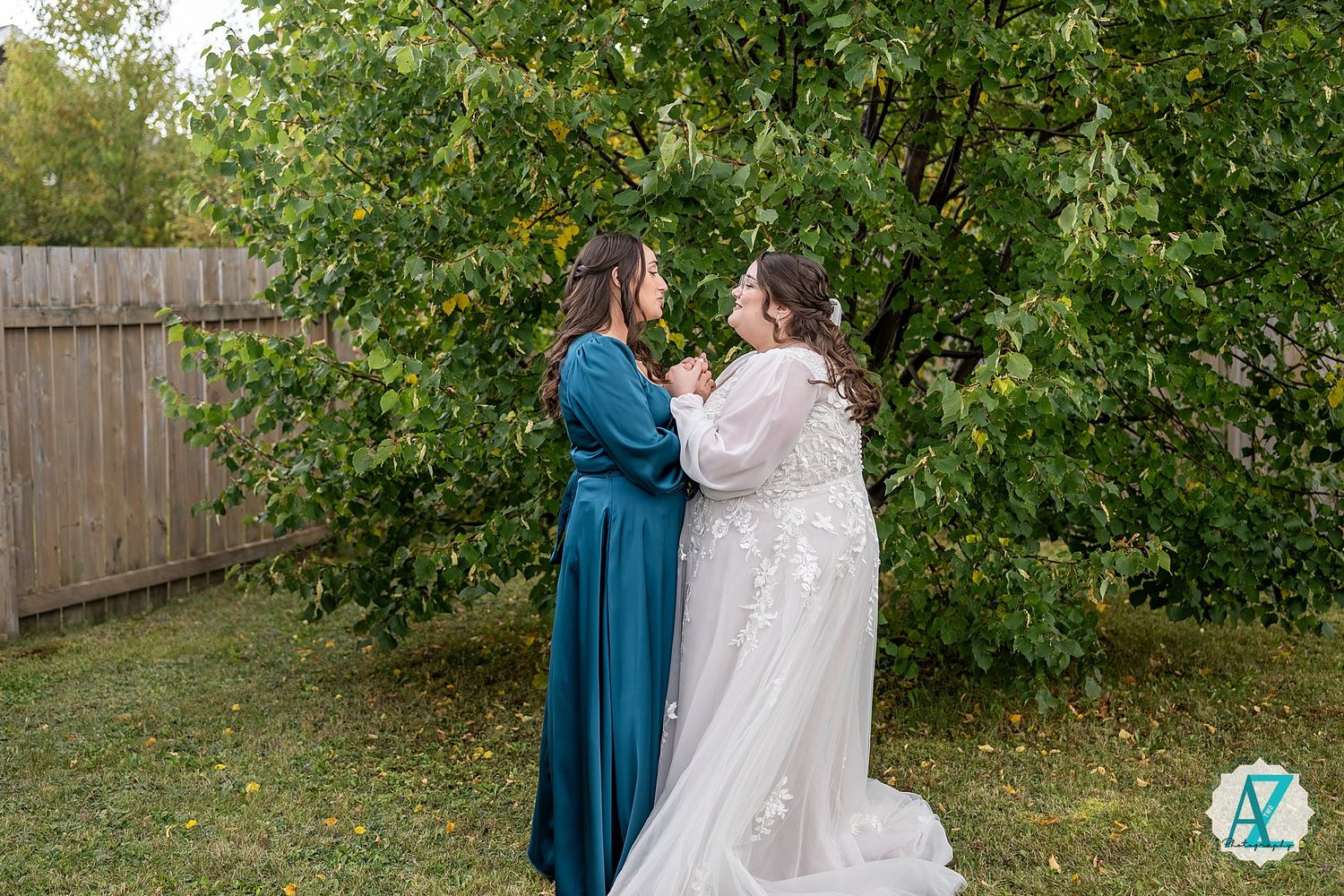 A couple in wedding attire shares a tender moment together in a garden setting with green foliage in the background.