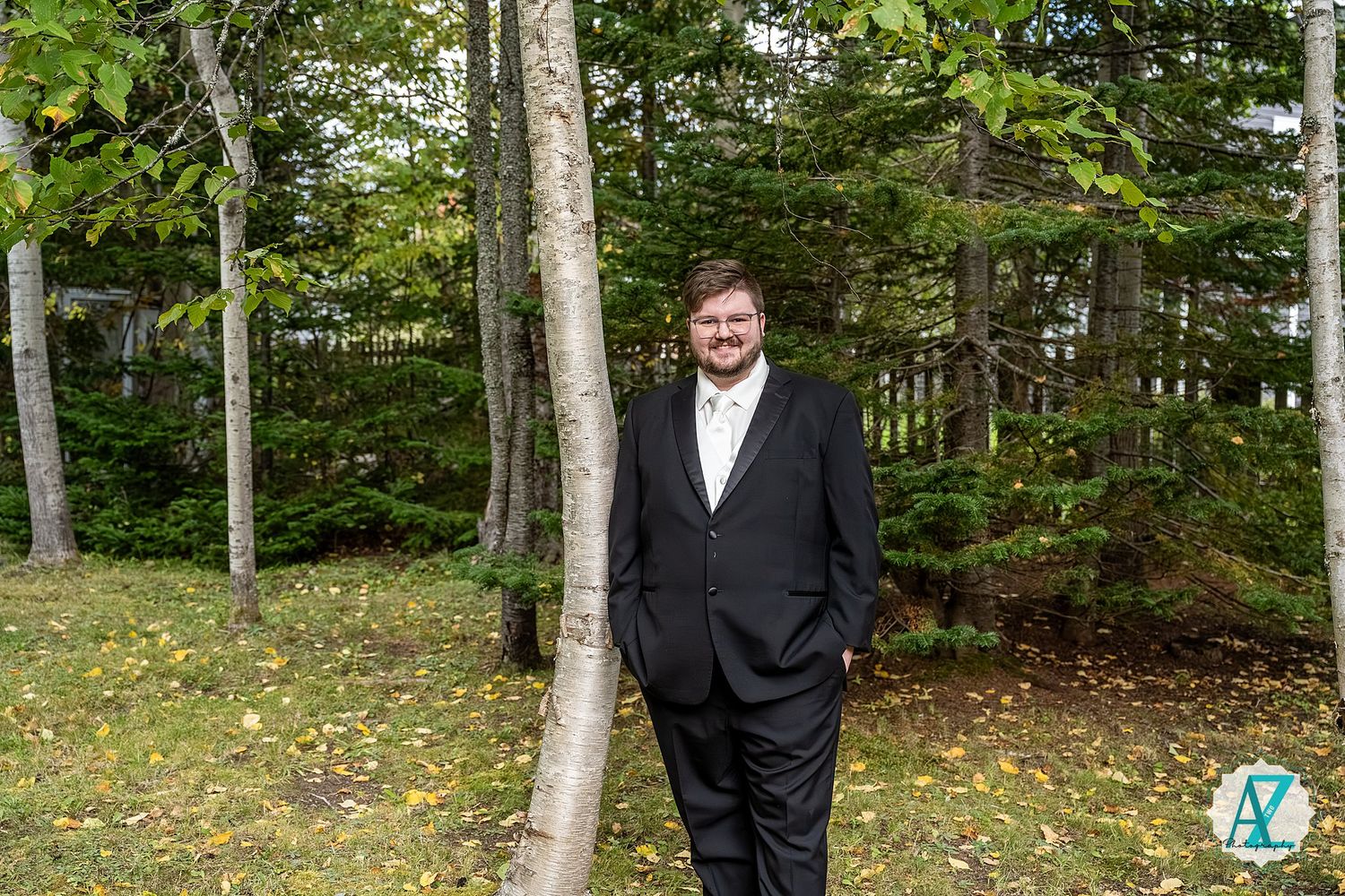 A formal portrait taken outdoors with birch trees and greenery in the background.