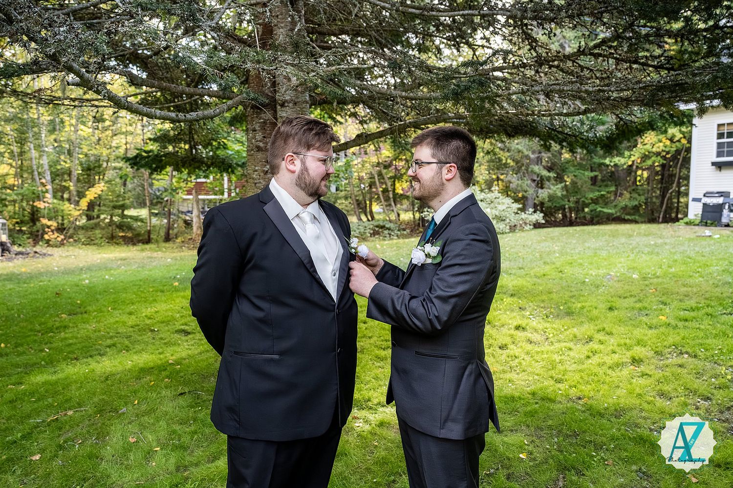 Wedding party members share candid moments while standing together in a wooded outdoor area.