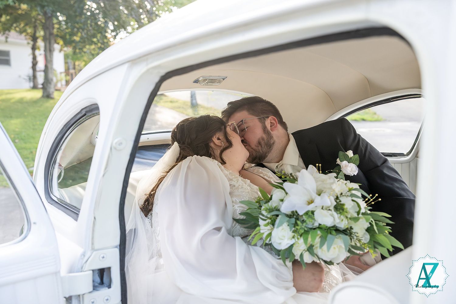 Newlywed couple sharing an intimate moment inside a classic white vintage car.