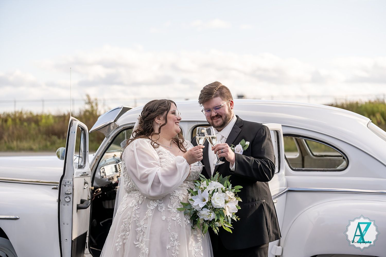 Elegant vintage automobile serves as backdrop for romantic wedding portraits in natural setting.