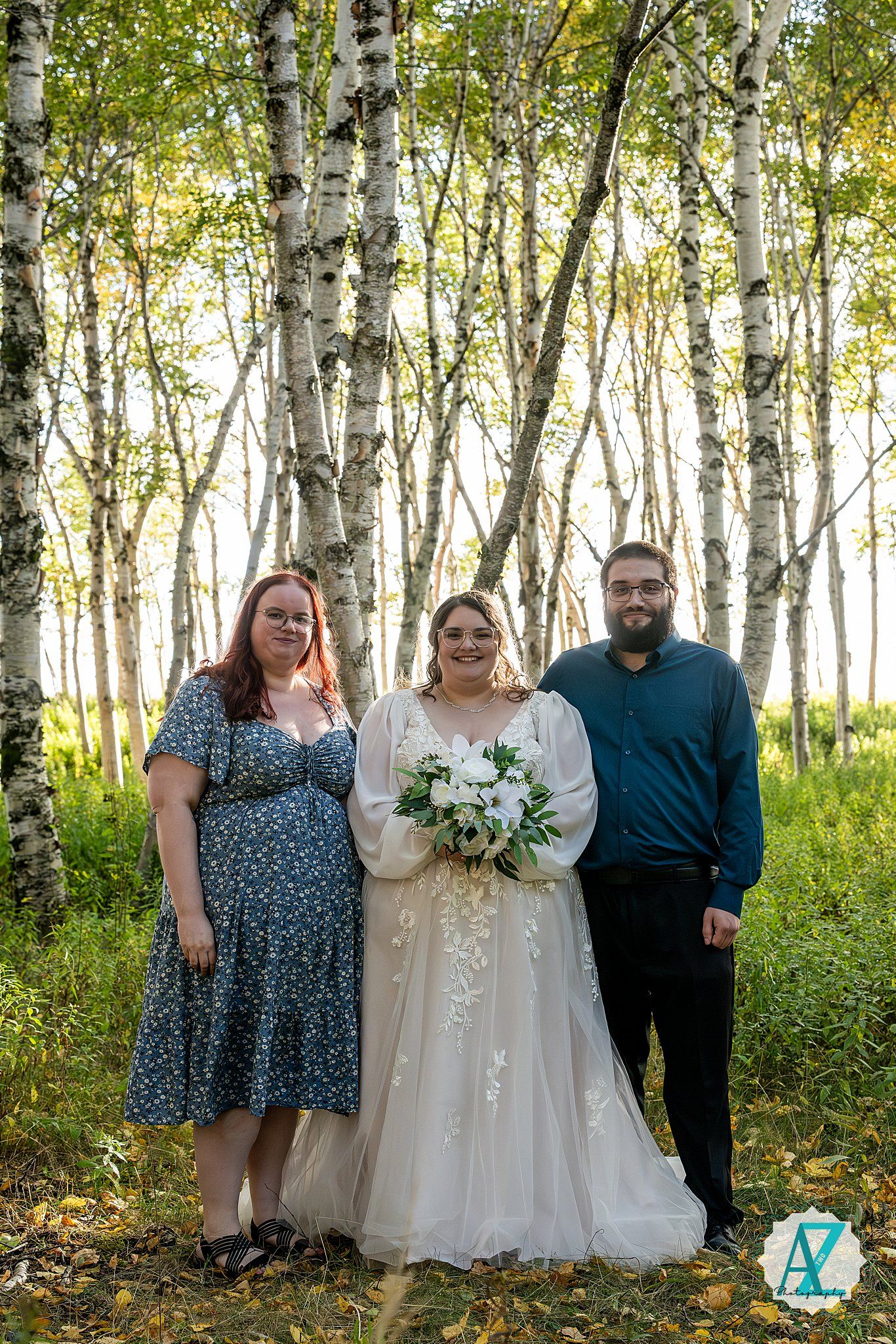 Wedding party poses together in a serene birch tree forest with sunlight filtering through the leaves.