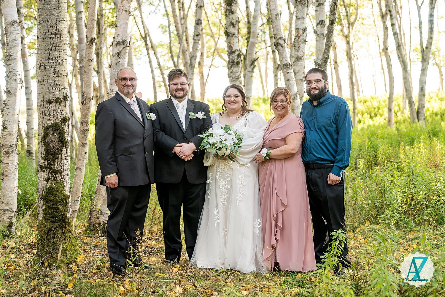 Family wedding portrait taken in a beautiful birch forest with golden sunlight filtering through.