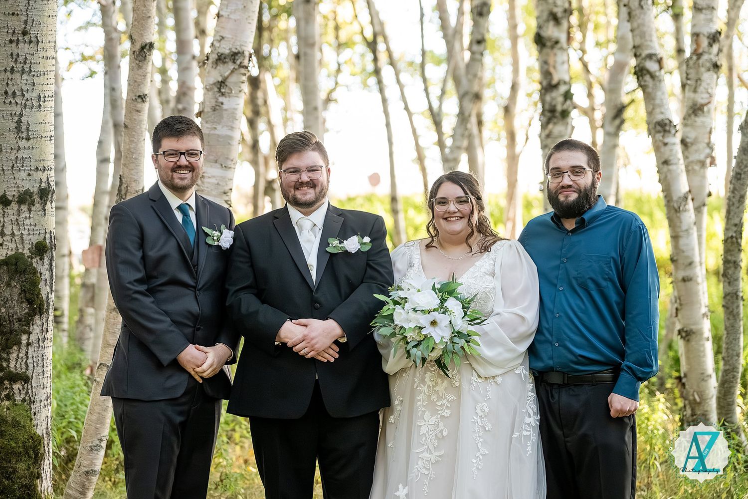 Wedding group photo with the wedding party standing together in a birch forest.