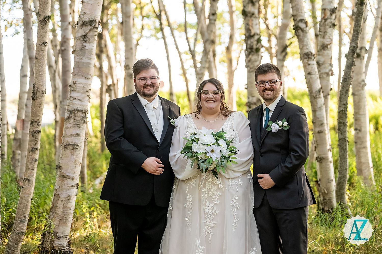 Wedding party poses together in a scenic birch tree forest during golden hour.