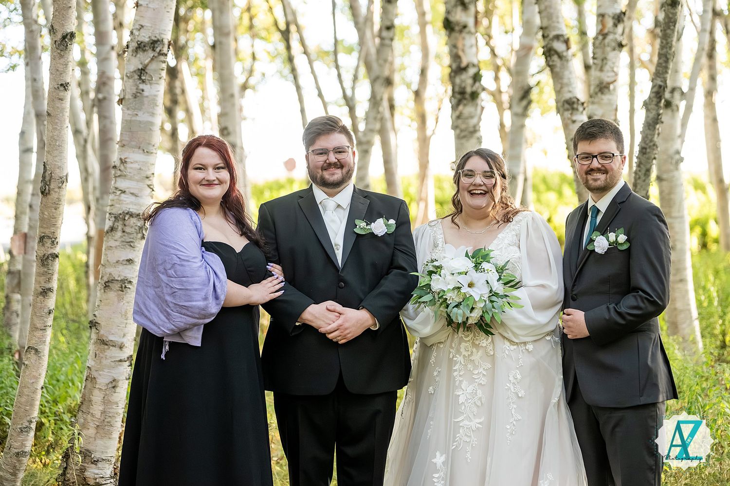 Bridal party stands in formation among white birch trees during an autumn wedding.