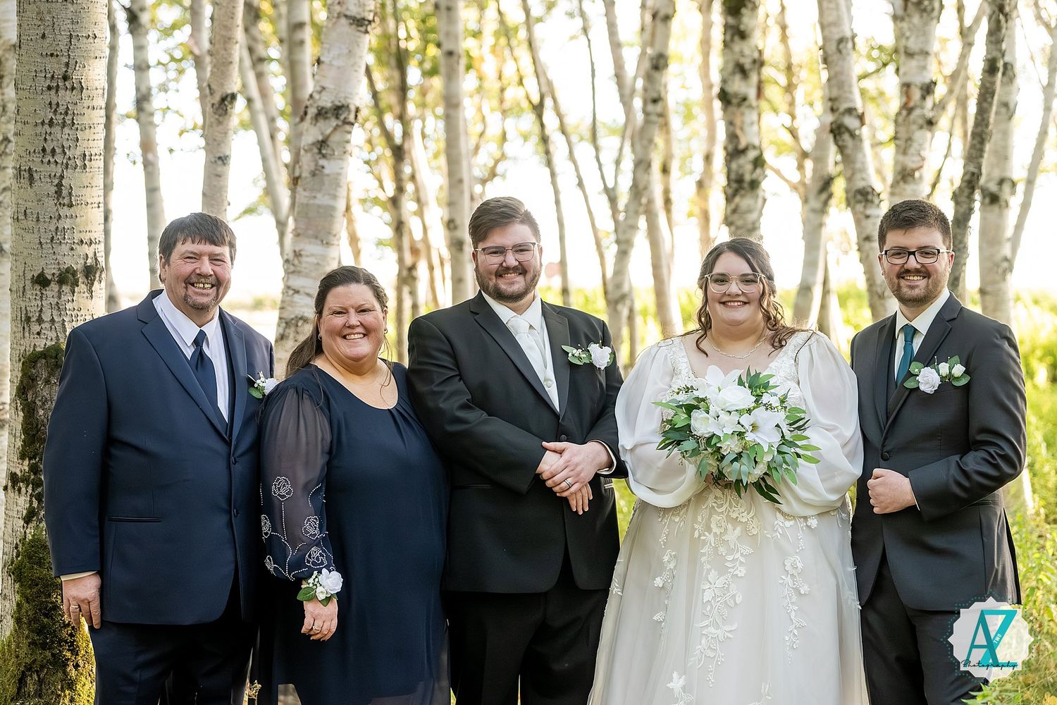 Wedding party poses together in a scenic birch forest setting on a bright autumn day.