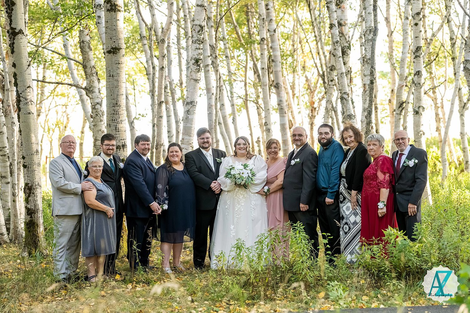 Extended family and wedding guests pose together in a picturesque birch tree forest setting.