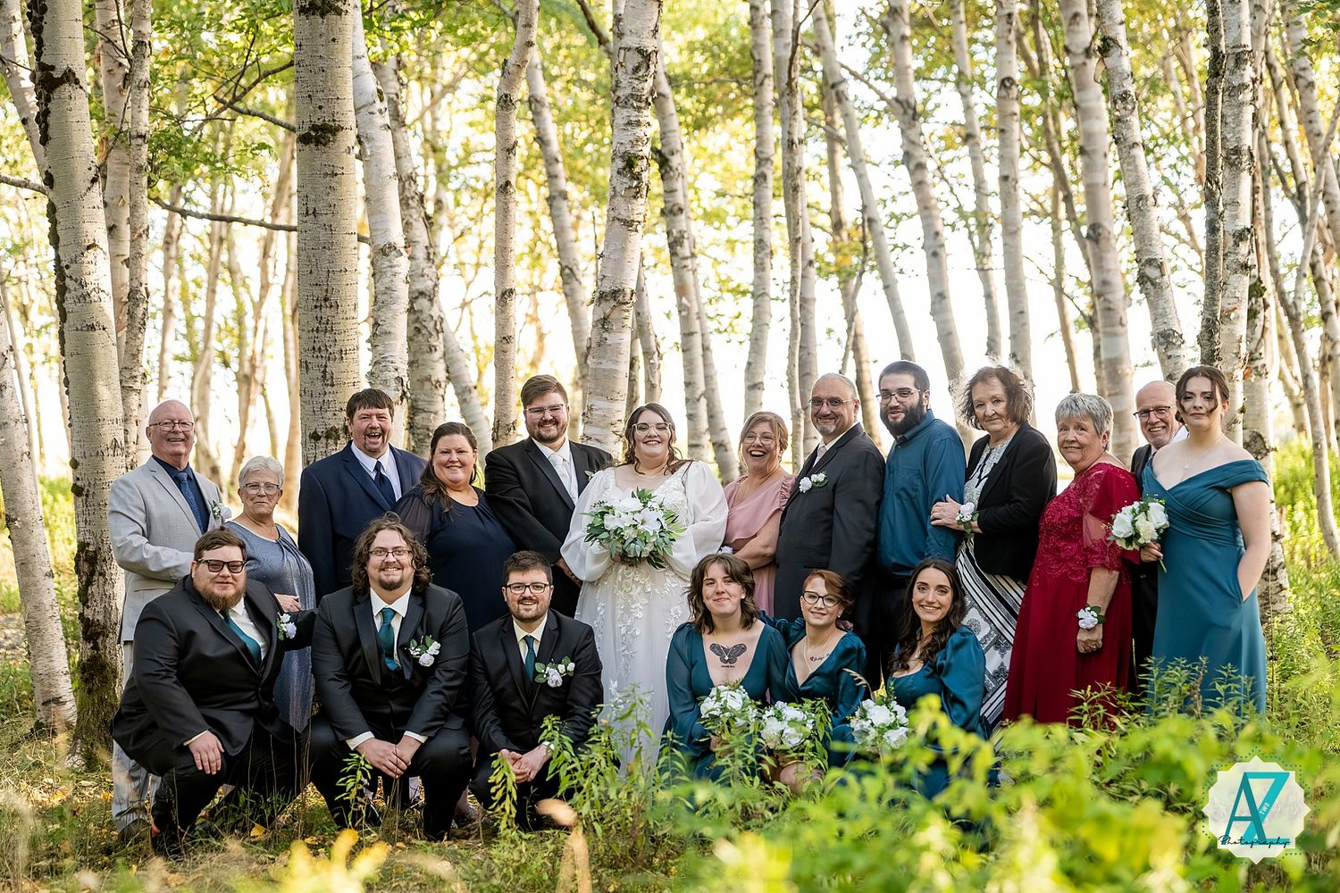 Wedding party poses together in a beautiful birch forest setting with golden sunlight filtering through the trees.