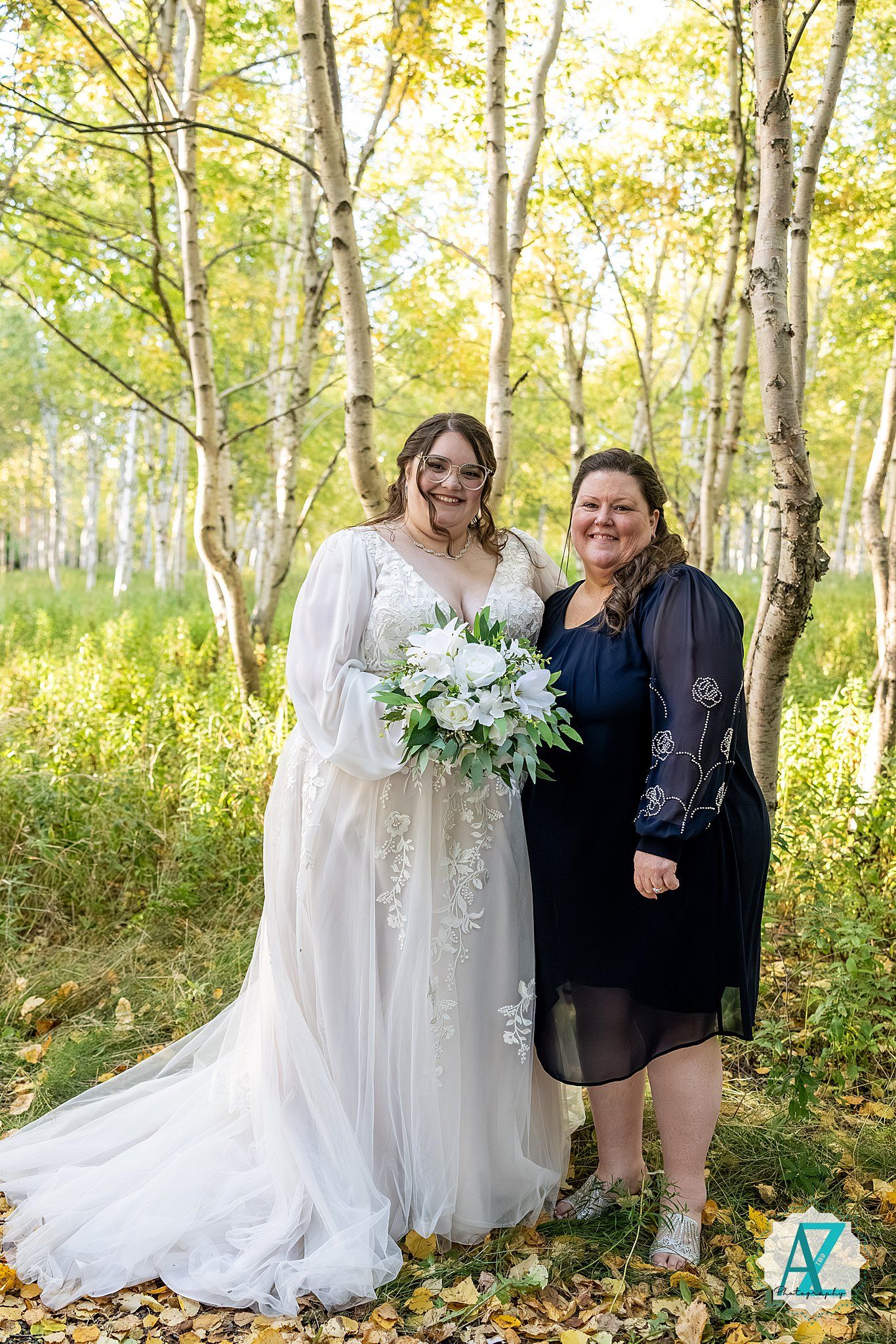Wedding party poses together in a scenic autumn birch forest with golden leaves and white floral bouquets.