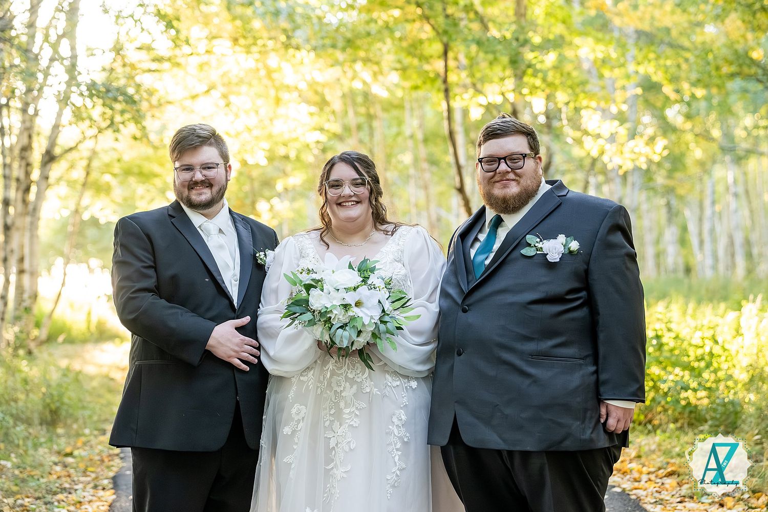 Wedding photo taken outdoors with autumn trees and golden sunlight in the background.