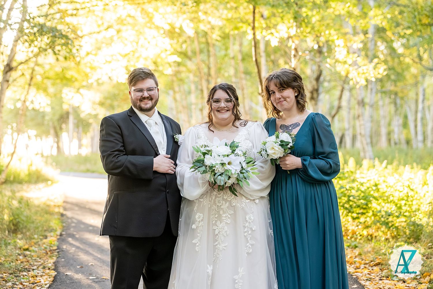 Small wedding group poses in golden afternoon light among white birch trees.
