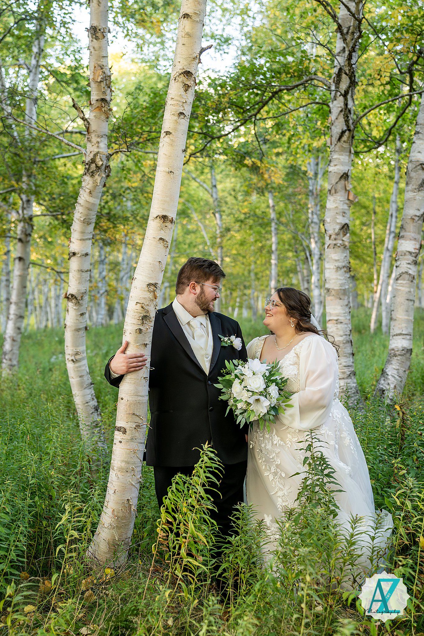 A romantic wedding photo shoot in a serene birch forest with sunlit trees and tall grass.