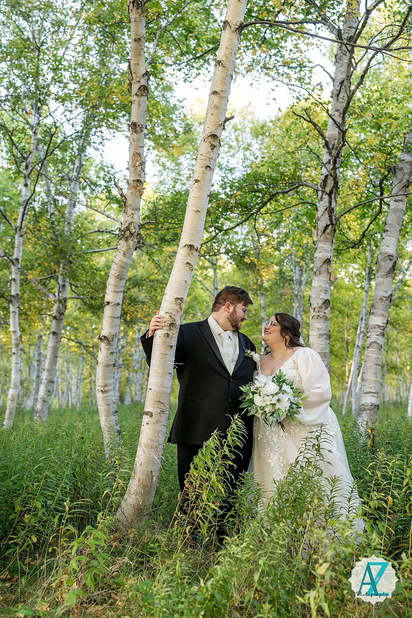 Couple shares intimate moment in beautiful birch tree grove with natural greenery.