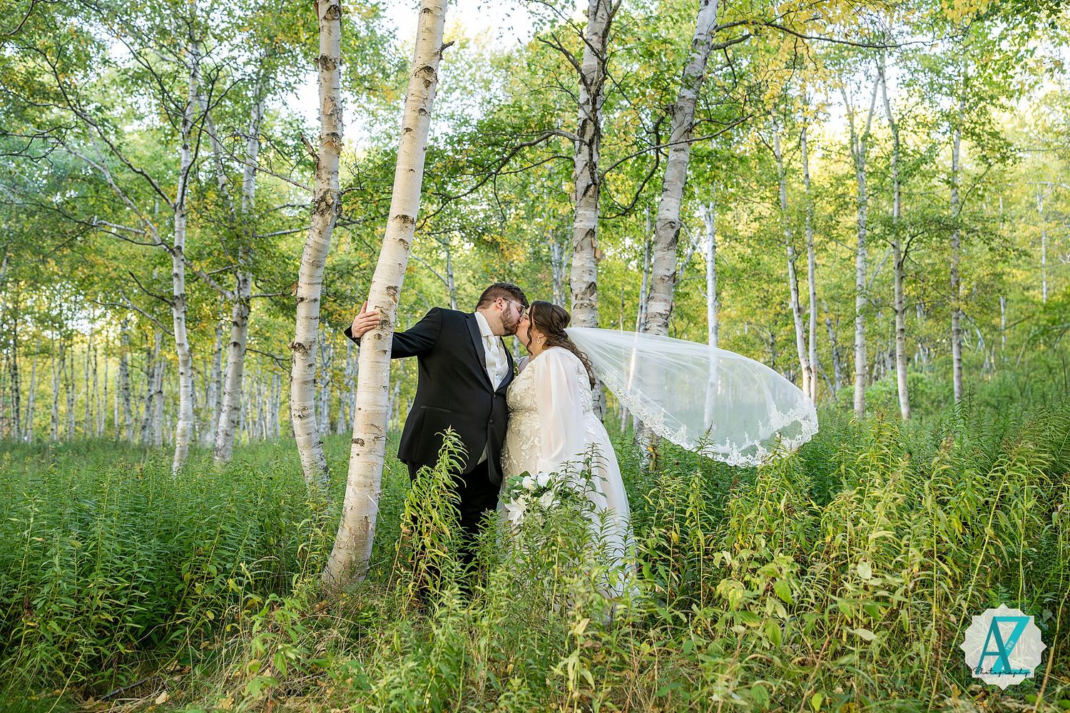 Newlyweds walk through a scenic birch forest with sunlight filtering through the leaves during their wedding celebration.