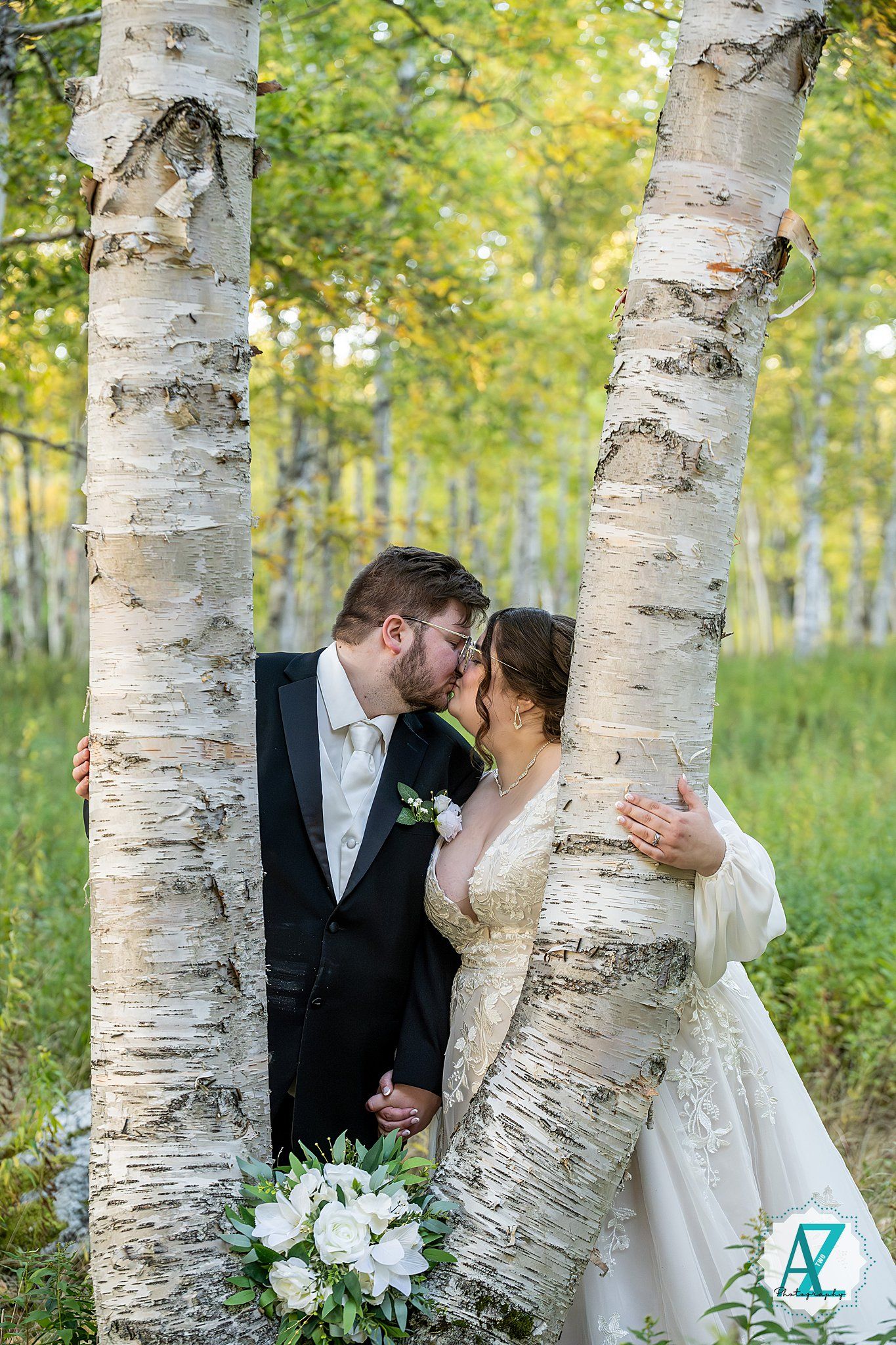 Intimate wedding photos captured between white birch trees in a lush summer forest.