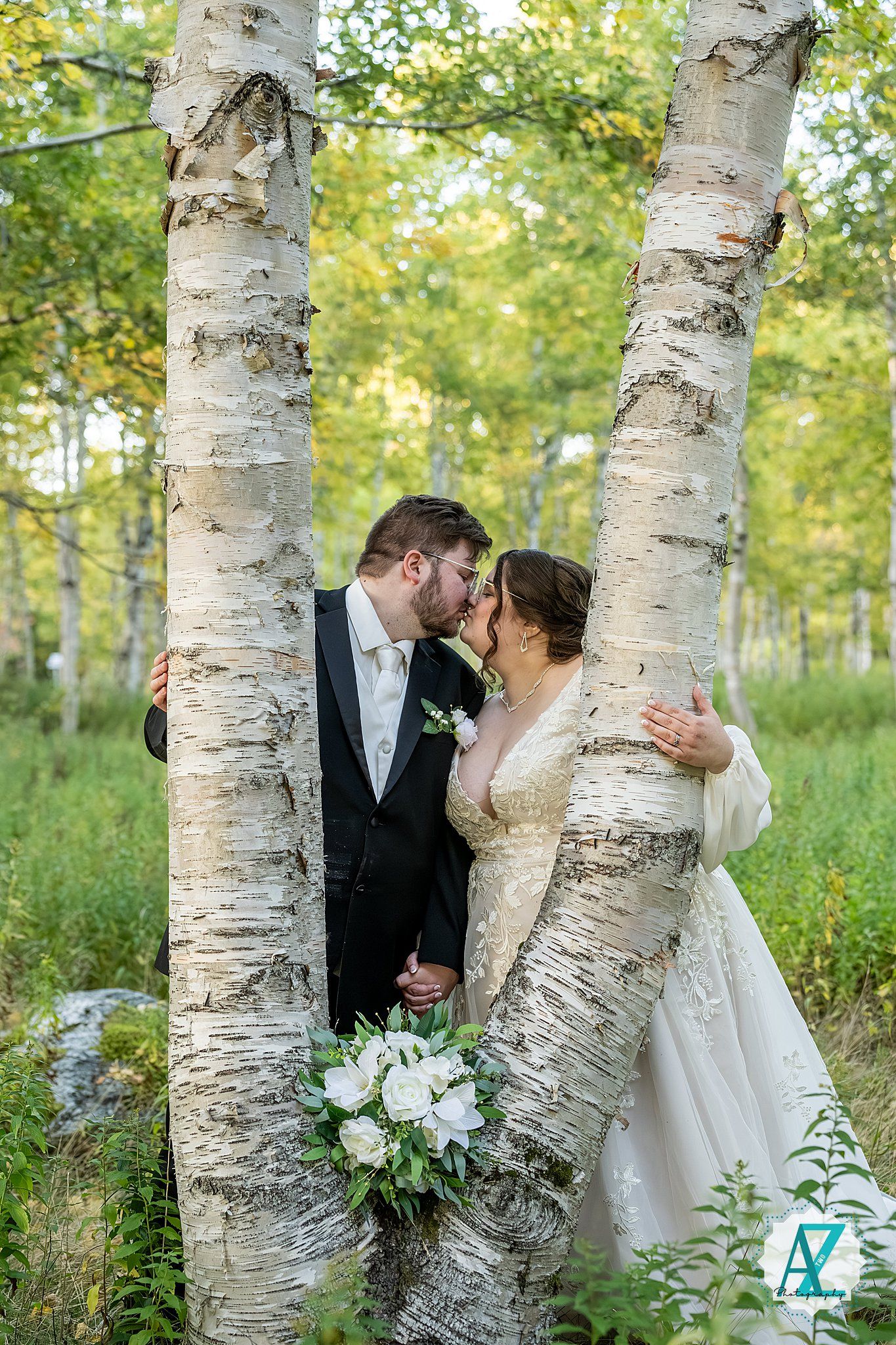 Romantic wedding couple shares intimate moments between birch trees in a sunlit forest setting.