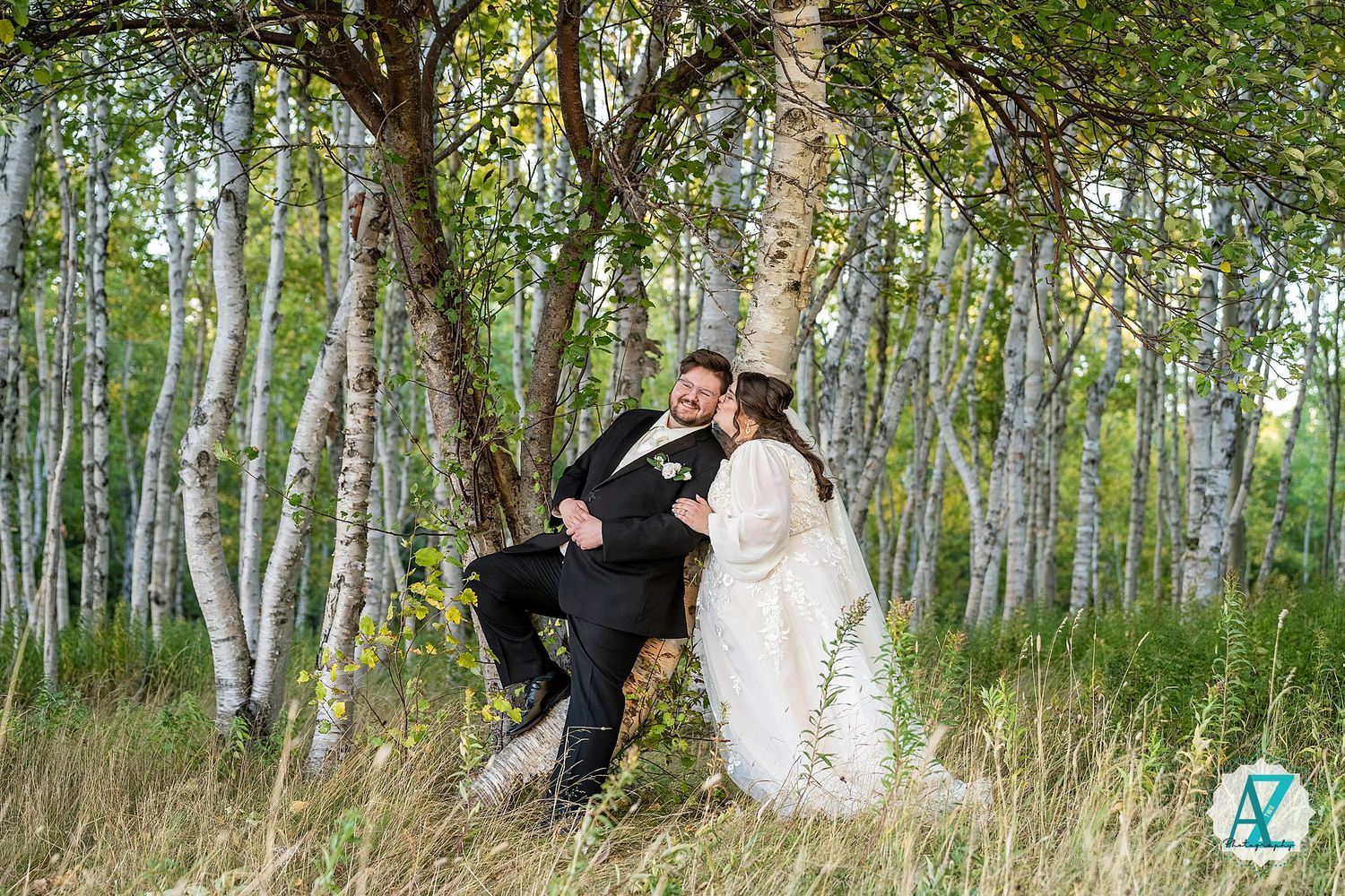 Wedding couple shares intimate moments among white birch trees in a natural forest setting.