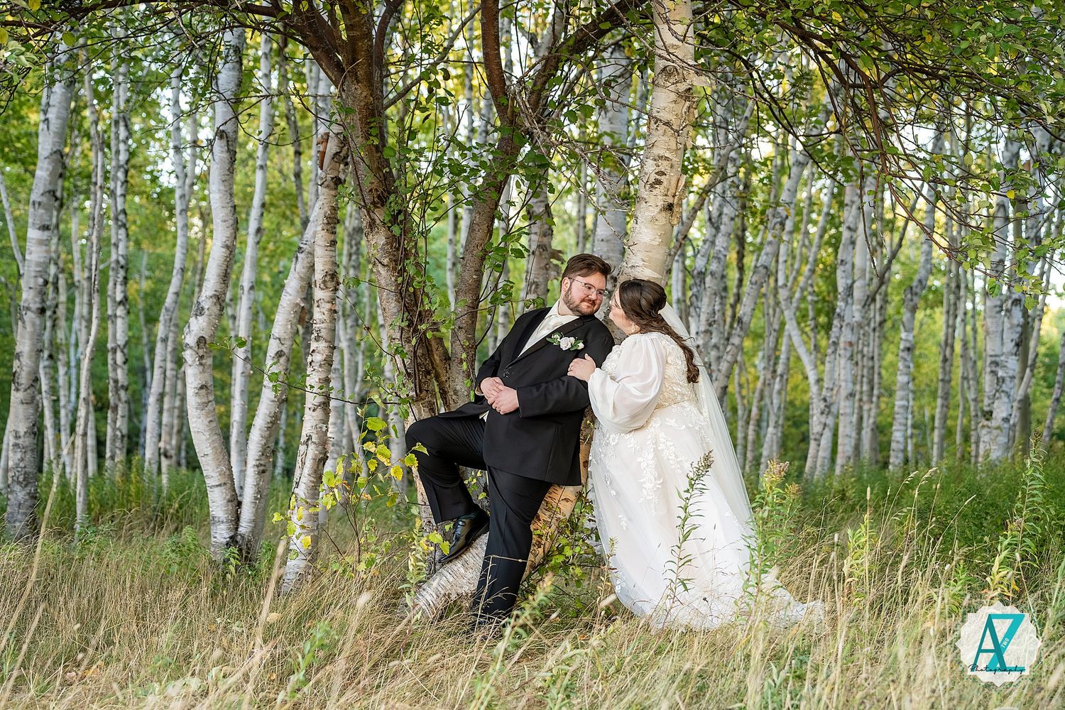 Wedding party poses among tall birch trees in a natural forest setting during an outdoor celebration.