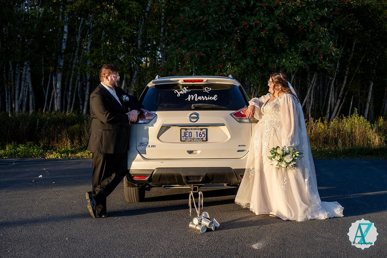 Wedding guests mingle during outdoor cocktail hour at sunset with cars parked in background.
