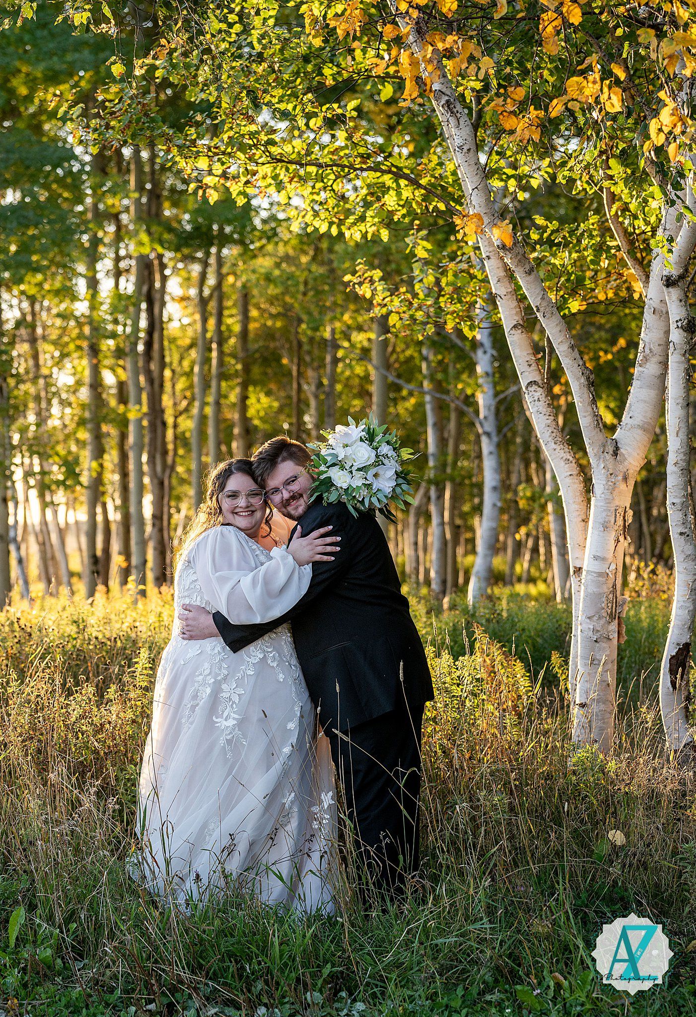 Couple shares romantic moment in white birch grove with tall grass and autumn foliage.