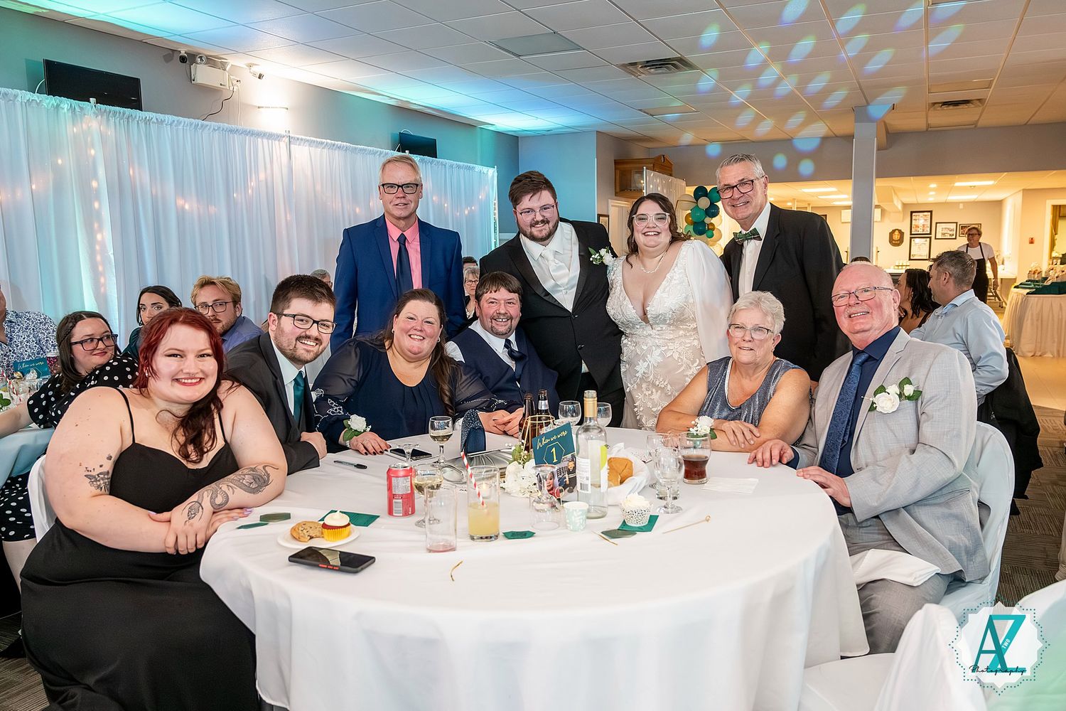 Wedding guests enjoying dinner and conversation at tables with blue ambient lighting.