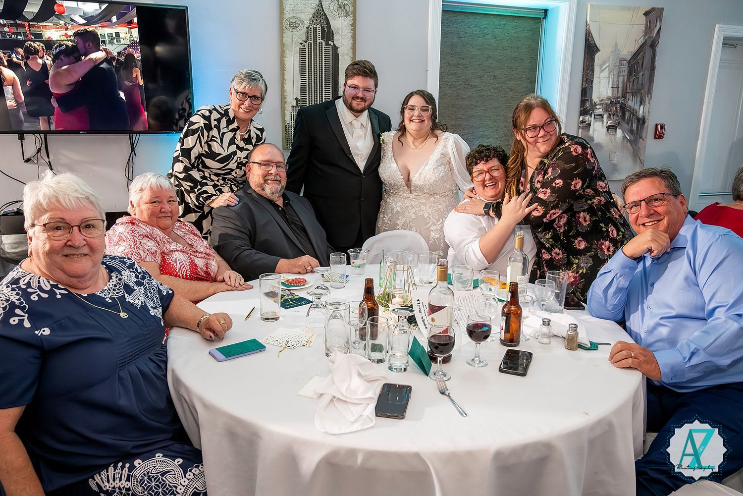 Wedding reception guests enjoying dinner and conversation at decorated round tables.