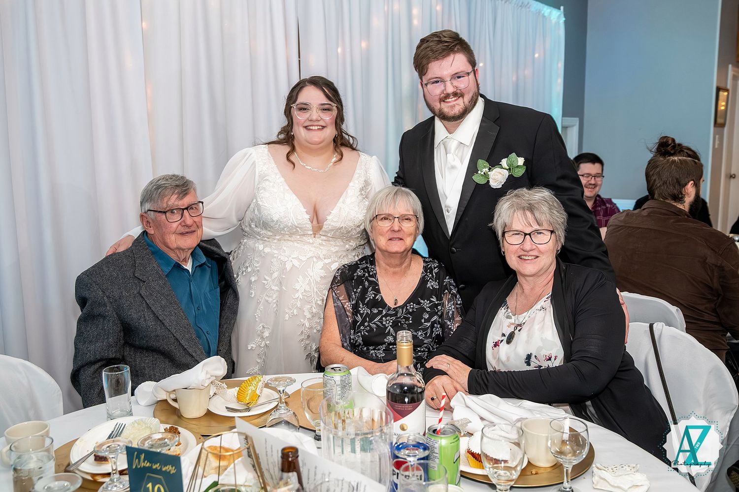 Wedding celebration with guests dining at elegantly set tables in a bright reception venue.