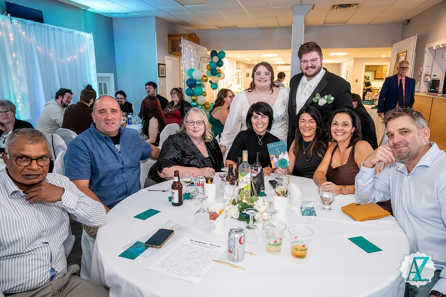 Large group of wedding guests seated at multiple tables during reception dinner.