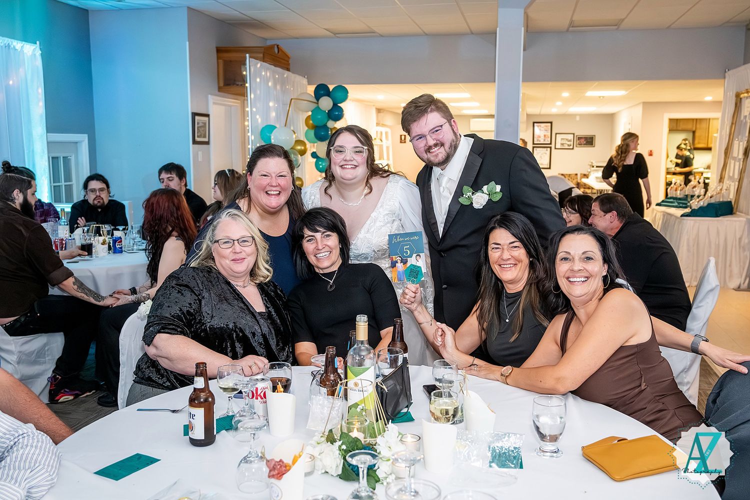 Panoramic view of wedding reception hall showing multiple guest tables with teal decor accents.