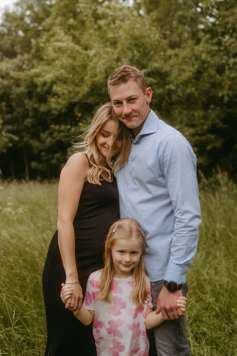Intimate family portrait in a meadow with soft evening lighting.
