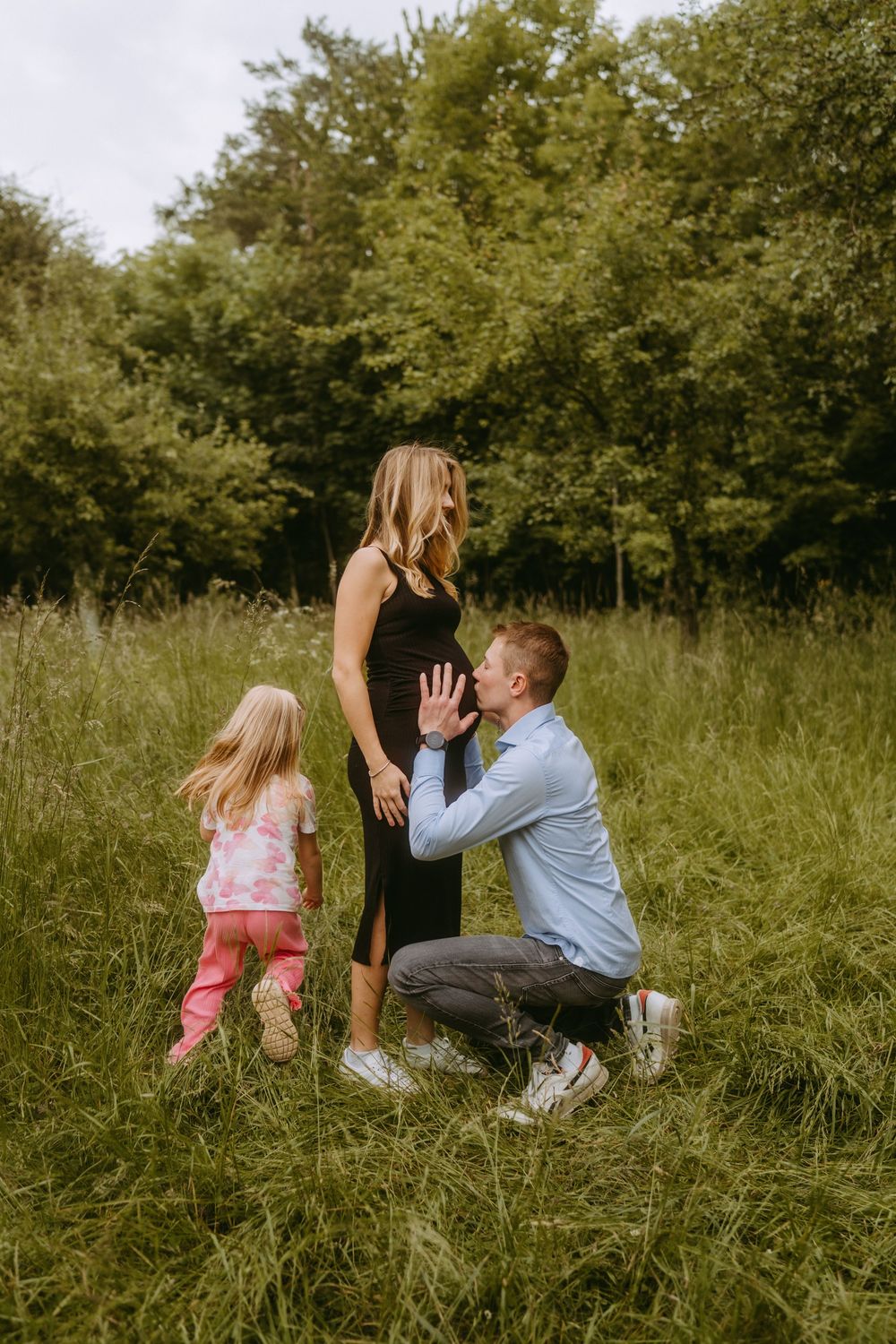 Family having fun and playing together in tall grass on a sunny day.
