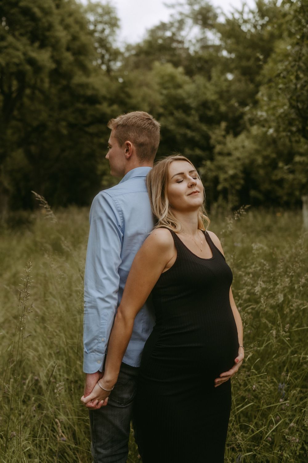 Artistic couple portrait with dramatic lighting in a natural outdoor setting.