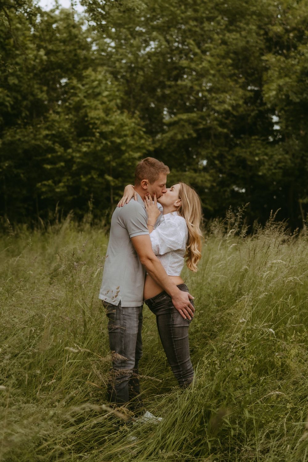 Intimate couple portrait in tall grass with warm sunset lighting.