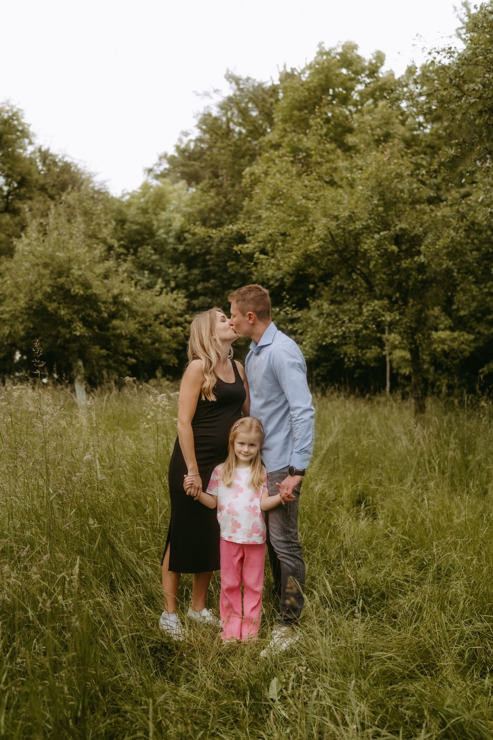 Family portrait session in a natural meadow setting during golden hour.