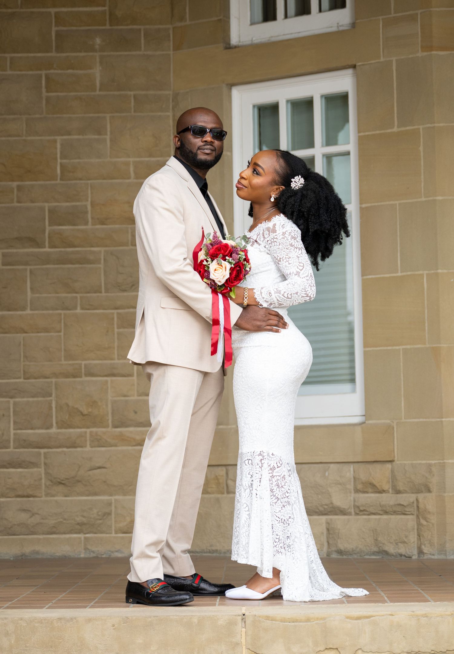 Romantic wedding photos of couple in white attire embracing on stone porch.
