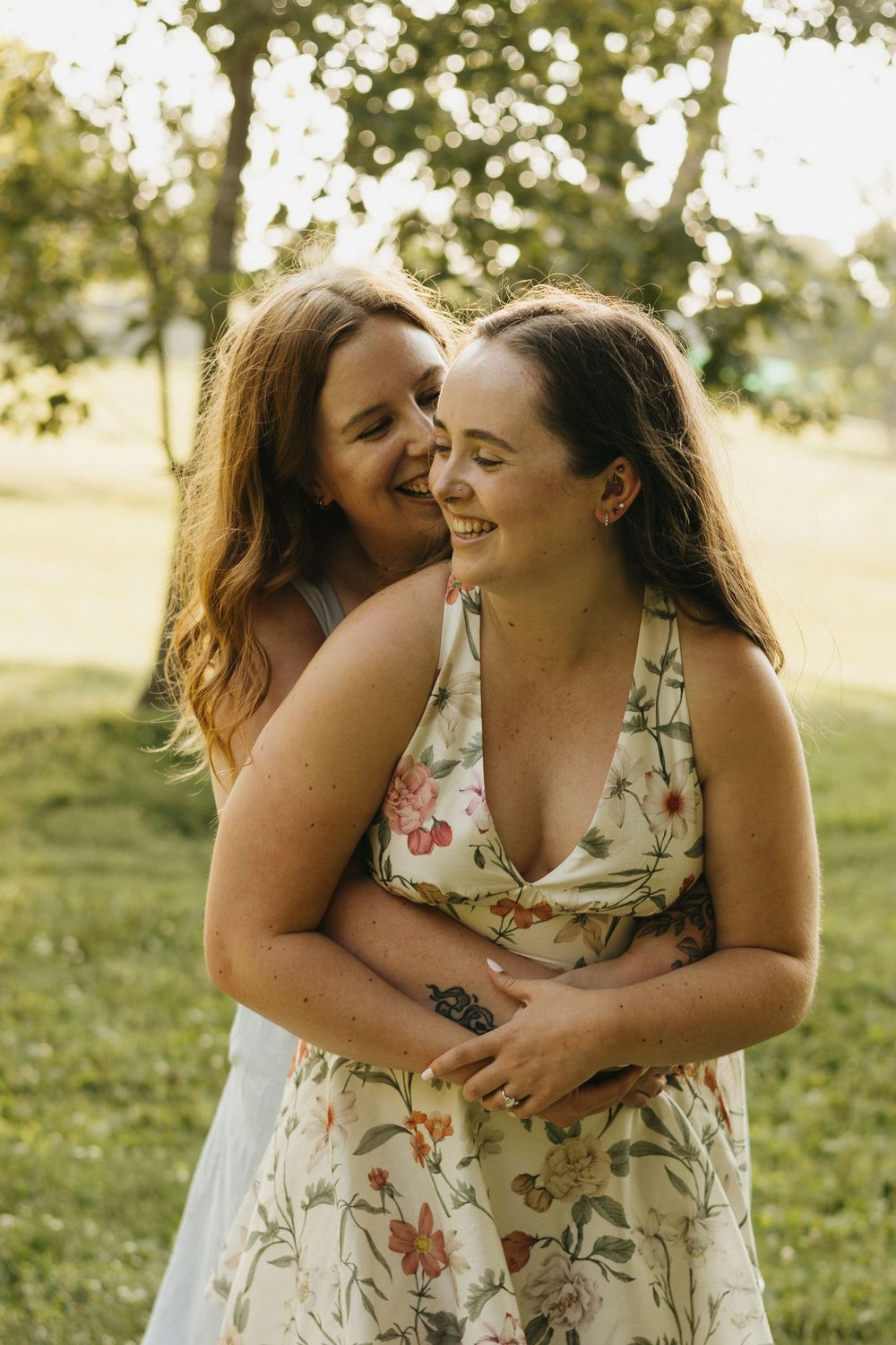 Two friends share a joyful embrace while laughing together outdoors on a sunny summer day in Waterloo Park