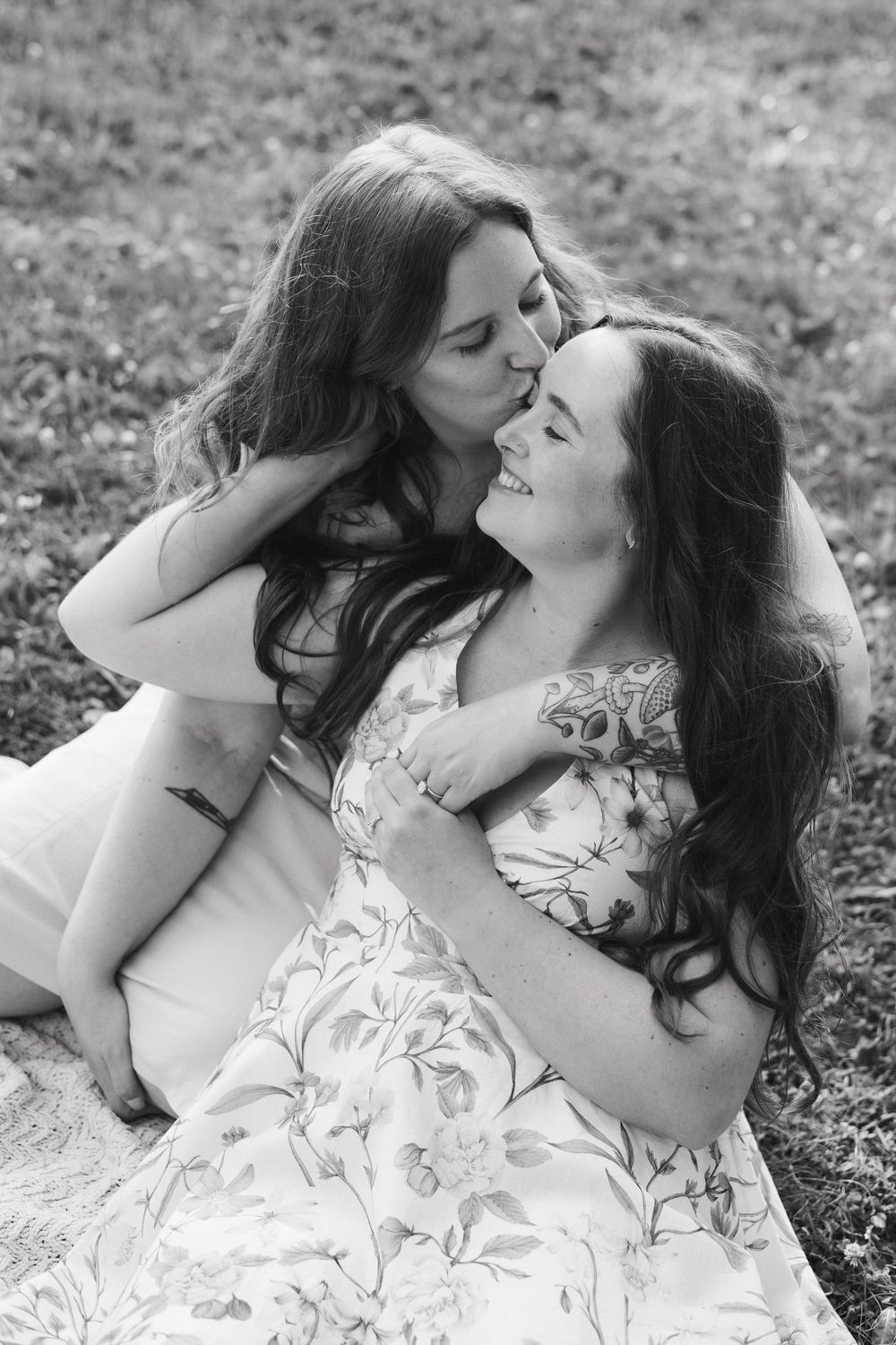 A romantic black and white photo series showing a couple lying in grass with flowing white fabric and natural lighting.