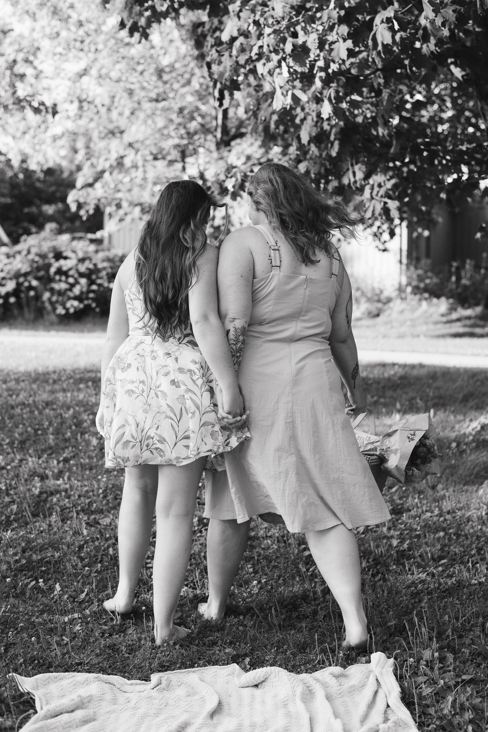 Cropped view of people sitting together on grass in light summer dresses in Waterloo Park