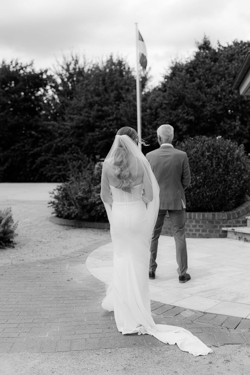 Black and white photo sequence of a couple walking away on a brick path with the bride's veil flowing in the wind.