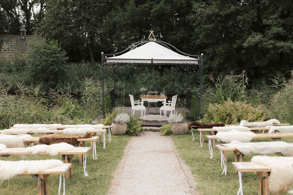 Outdoor garden seating area with white picnic tables arranged along a winding path surrounded by lush greenery.